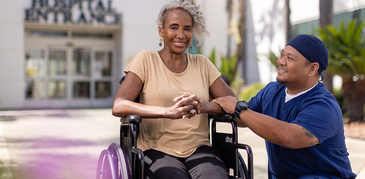 Woman in wheelchair with healthcare professional beside her